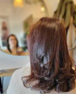 Cheveux longs châtain avec wavy léger, vue de dos devant un miroir